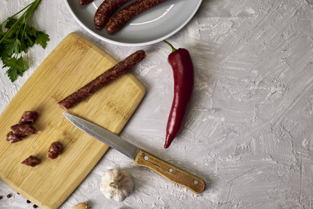 spicy smoked sausages on a cutting board next to red pepper garlic spices and herbs on the table copy space . high quality photoの写真素材