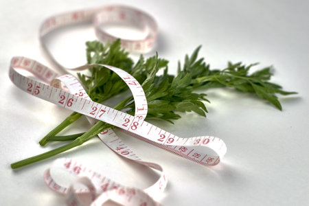 green parsley leaves wrapped with measuring tape on a white background concept diet vegetarianism. high quality photoの写真素材