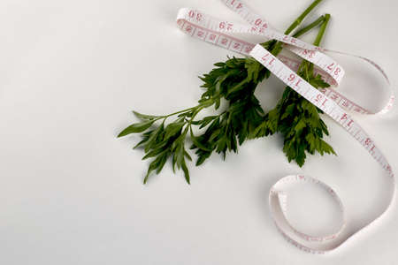 green parsley leaves wrapped with measuring tape on a white background concept diet vegetarianism. high quality photoの写真素材