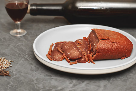 sliced basturma on a plate next to a bottle of wine and a glass. high quality photo
