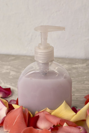 rose petals and a bottle of liquid soap on a gray textured background. high quality photoの写真素材