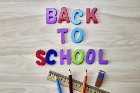 the phrase back to school is laid out in multicolored letters on the table next to colored pencils...