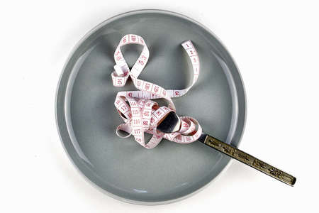 a measuring tape wound on a fork on a plate diet concept. high quality photoの写真素材