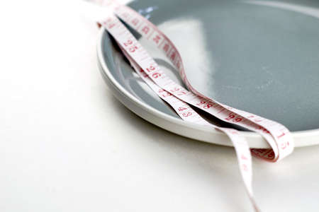 gray plate rewound with measuring tape concept diet. high quality photoの写真素材