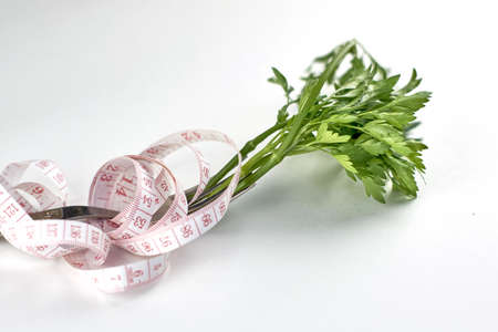 green parsley leaves measuring tape and fork on a white background concept diet vegetarianism veganism. high quality photoの写真素材