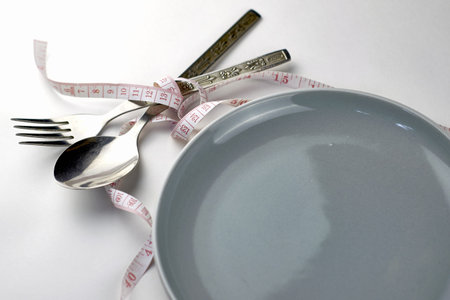 plate fork and spoon wrapped with measuring tape concept diet. high quality photo
