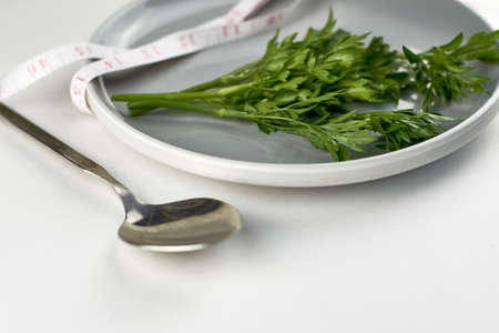a plate of greens wrapped with a measuring tape, next to a spoon the concept of vegetarianism vegan diet. high quality photoの写真素材