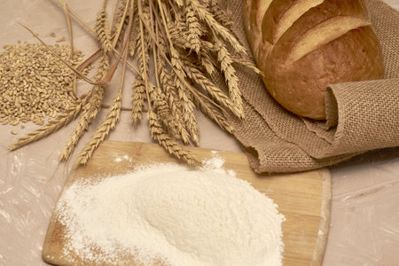 a loaf of bread on burlap flour grain and ears of wheat. high quality photoの写真素材