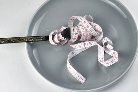 a measuring tape wound on a fork on a plate diet concept. high quality photoの写真素材