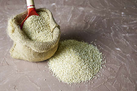 quinoa groats with a wooden spoon in a canvas bag on the table. high quality photoの写真素材