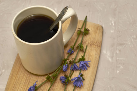 a mug with a drink and chicory flowers on a cutting board. high quality photoの写真素材