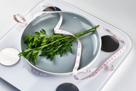 a plate of greens wrapped with a measuring tape, standing on the scales the concept of vegetarianism vegan diet. high quality photoの写真素材