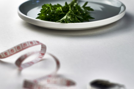 plate with greens fork and measuring tape on a white background with a space for copying, the concept of a vegetarian vegan diet. high quality photoの写真素材