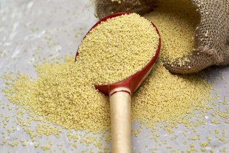 crop couscous spills out of a canvas bag and a wooden spoon on the table. high quality photoの写真素材