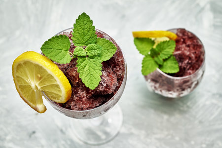 frozen red wine in two glass glasses decorated with a slice of lemon and lemon leaves. high quality photoの写真素材