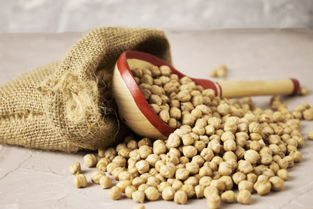 chickpeas in a canvas bag and a wooden spoon on the table. high quality photoの写真素材