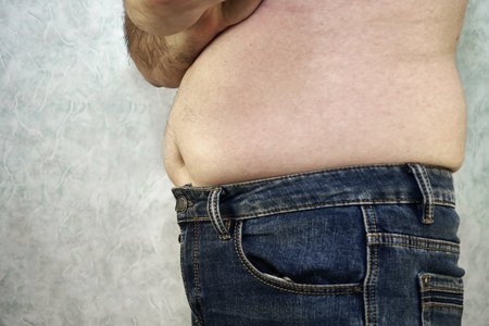 a man in jeans with a bare torso and a small belly close-up of the concept of overweight body positive. high quality photoの写真素材
