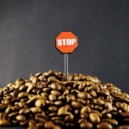 roasted coffee beans and a stop sign on a black background the concept of limiting coffee consumption. high quality photoの写真素材