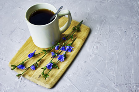 a mug with a drink and chicory flowers on a cutting board. high quality photoの写真素材