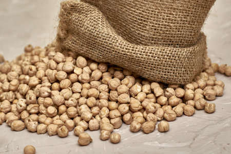 chickpeas in a canvas bag and scattered on the tableの写真素材