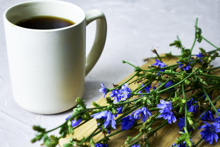 a mug with a drink and chicory flowers on a cutting board. high quality photoの写真素材