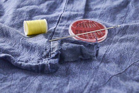 needles and thread on the background of torn jeans the concept of reasonable consumption of needlework for small businesses. high quality photoの写真素材