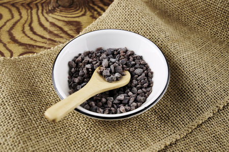Black salt Kala namak in a salt shaker with a wooden spoon on a burlap. high quality photoの写真素材