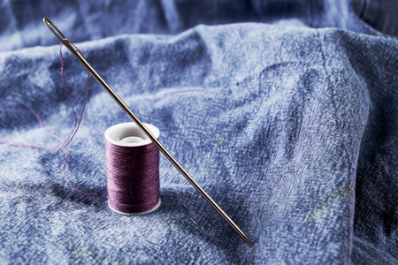 needles and thread on the background of torn jeans the concept of reasonable consumption of needlework for small businesses. high quality photoの写真素材