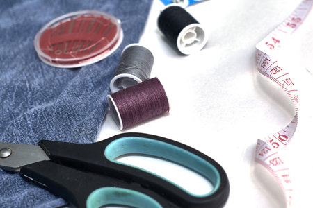 scissors needles measuring tape and thread on the background of torn jeans the concept of reasonable...