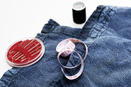 needles measuring tape and thread on the background of torn jeans the concept of reasonable consumption of needlework for small businessesの写真素材