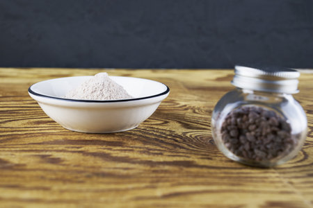 Black salt Kala namak in a glass salt shaker and on a plate on a wooden tableの写真素材