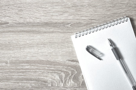 an open notepad for notes and a pen on a wooden table with a copy space top view