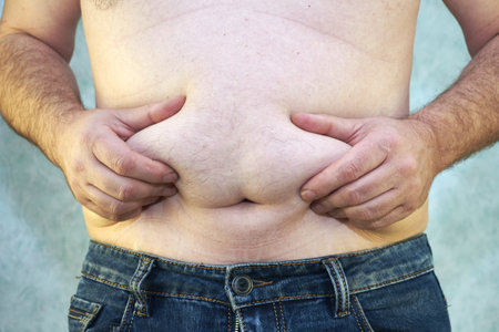 a man in jeans with a bare torso and a small belly close-up of the concept of overweight body positiveの写真素材