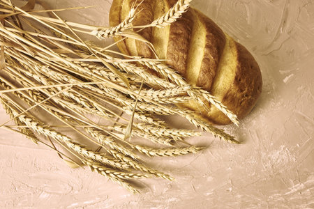 a loaf of bread and ears of wheat on the table