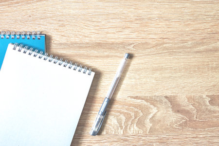 two notebooks for notes and a pen on a wooden table with a copy space top viewの写真素材