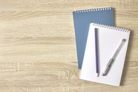two notebooks for notes a pencil and a fountain pen on a wooden table with a copy space top view. high quality photoの写真素材