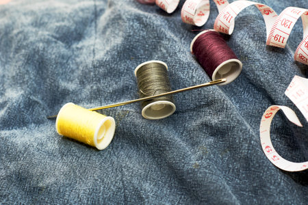 needles measuring tape and thread on the background of torn jeans the concept of reasonable consumption of needlework for small businesses. high quality photoの写真素材