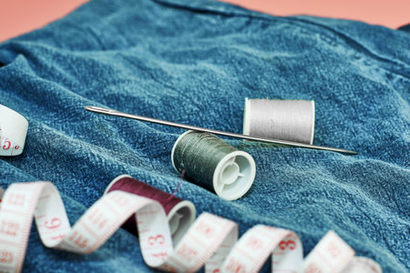 needles measuring tape and thread on the background of torn jeans the concept of reasonable consumption of needlework for small businessesの写真素材