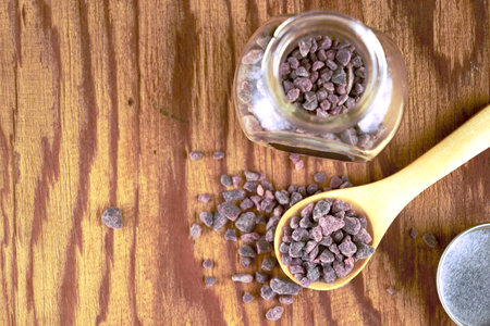 Black salt Kala namak in a glass salt shaker and on a wooden spoon on the tableの写真素材