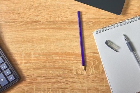an open notepad for notes, a fountain pen, a pencil calculator and a laptop on a wooden table with a copy space top viewの写真素材
