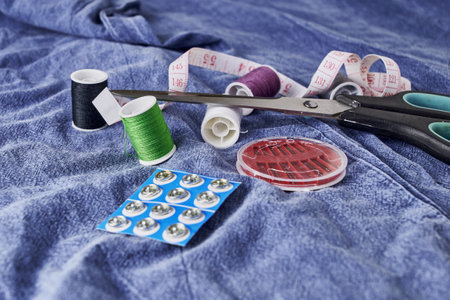scissors needles measuring tape and thread on the background of torn jeans the concept of reasonable consumption of needlework for small businessesの写真素材