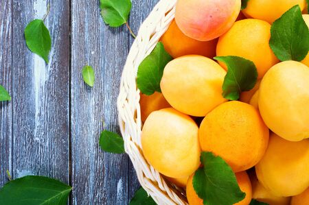 ripe juicy apricots in a basket on a wooden backgroundの写真素材
