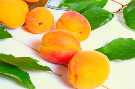 Fresh juicy apricots in the leaves on the wooden backgroundの写真素材