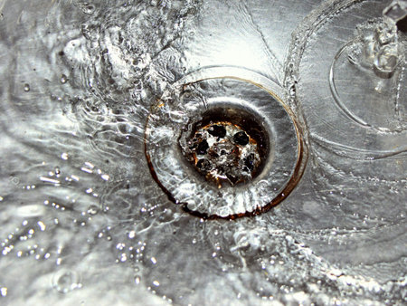The flow of water in the sink pours into the drain