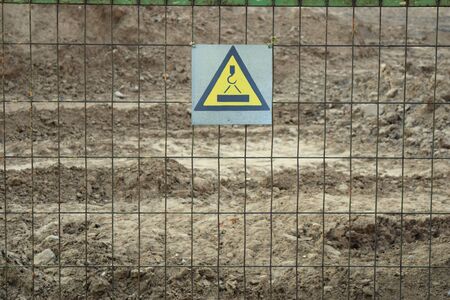 Trellised fence with a warning sign that the crane is workingの写真素材