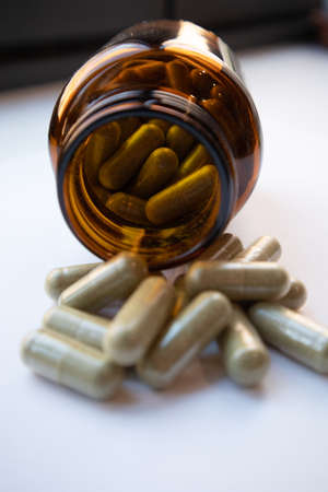 A pile of olive leaf supplement capsules with the supplement bottle.の写真素材