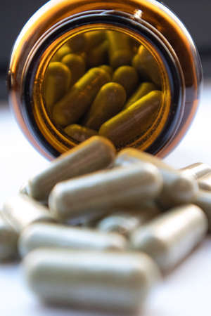A pile of olive leaf supplement capsules with the supplement bottle.の写真素材