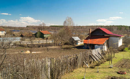 Rural landscape in village by springtime on background blue sky and white cloudの写真素材