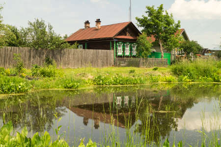 Year rural landscape with lake and wooden house on background blue skyの写真素材