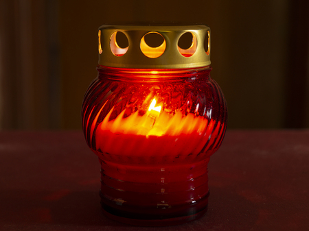 Candle blazes in glass form with metallic lid on dark backgroundの写真素材